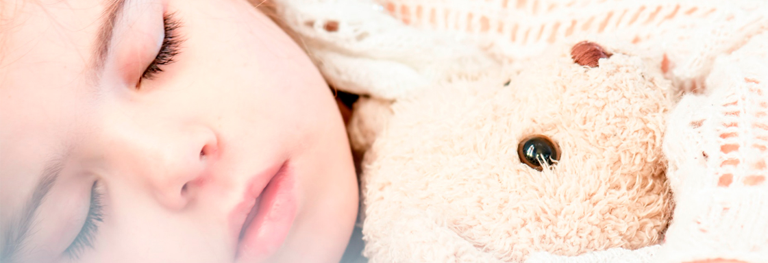 Niña dormida abraza a un oso de peluche