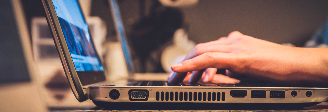 Las manos de una persona están en el teclado de una computadora portátil