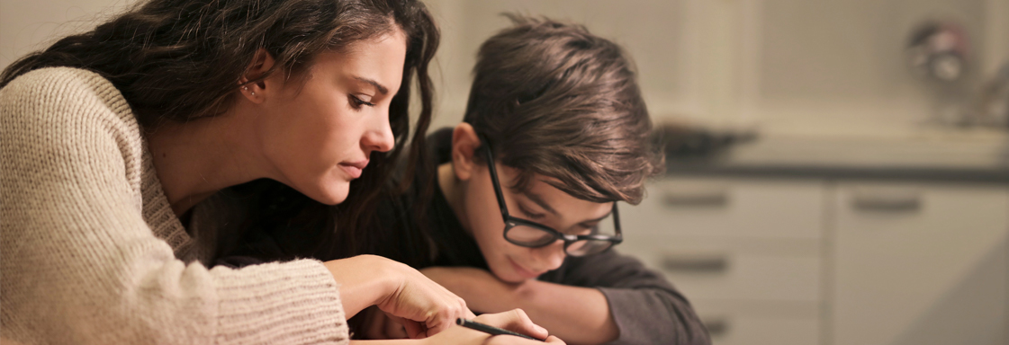 Fotografía de dos jóvenes, un hombre y una mujer, haciendo tarea en una misma libreta.