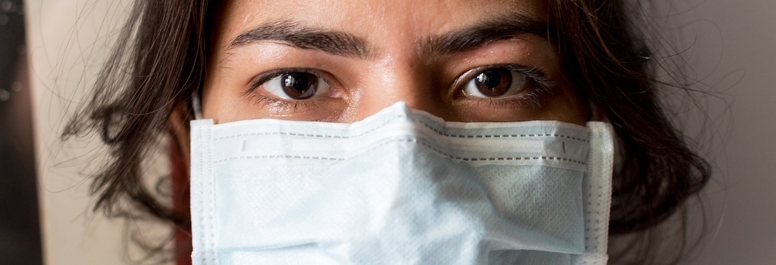 Fotografía de una mujer morena utilizando un cubrebocas tricapa azul. Créditos: Pixabay.